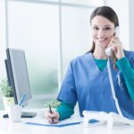 Smiling nurse on phone at reception desk