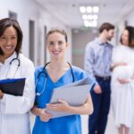 Doctor and nurse with expectant couple in hallway