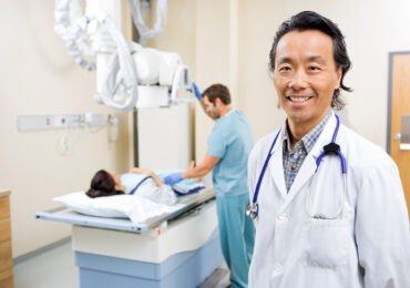 Smiling doctor in X-ray room with patient
