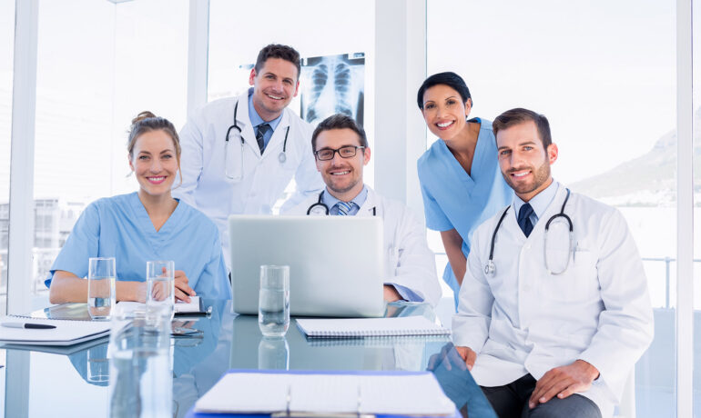 Smiling medical team gathered around conference table
