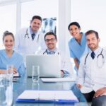 Smiling medical team gathered around laptop