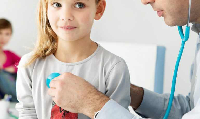 Pediatrician examining young girl with stethoscope