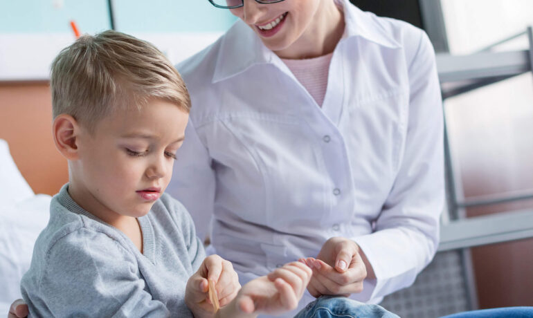 Pediatrician examining young boy's wrist